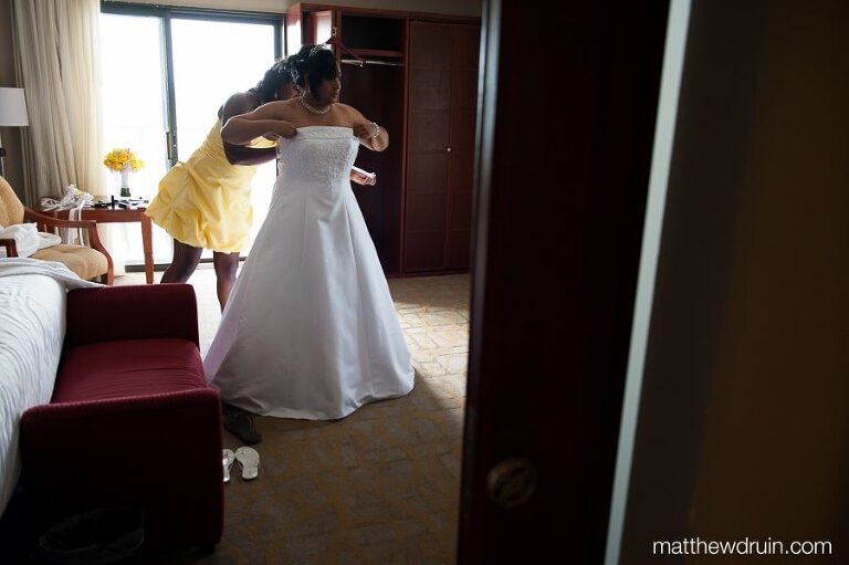 Bridesmaid wearing yellow dress helping bride put on her wedding dress while getting ready for Puerto Rico wedding