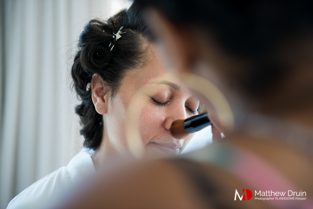 Makeup artist putting makeup on bride shot through earring at The Peachtree Club wedding