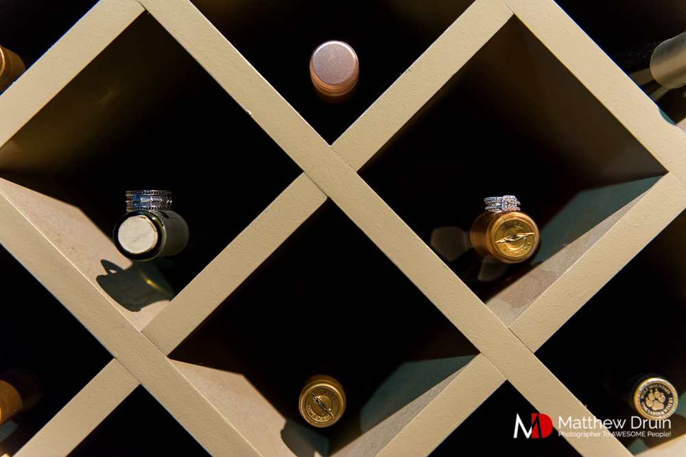Bride and groom's rings on wine bottles in wine rack at The Peachtree Club wedding