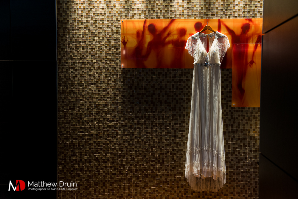 Bride's wedding dress hanging on orange wall artwork at The Peachtree Club wedding