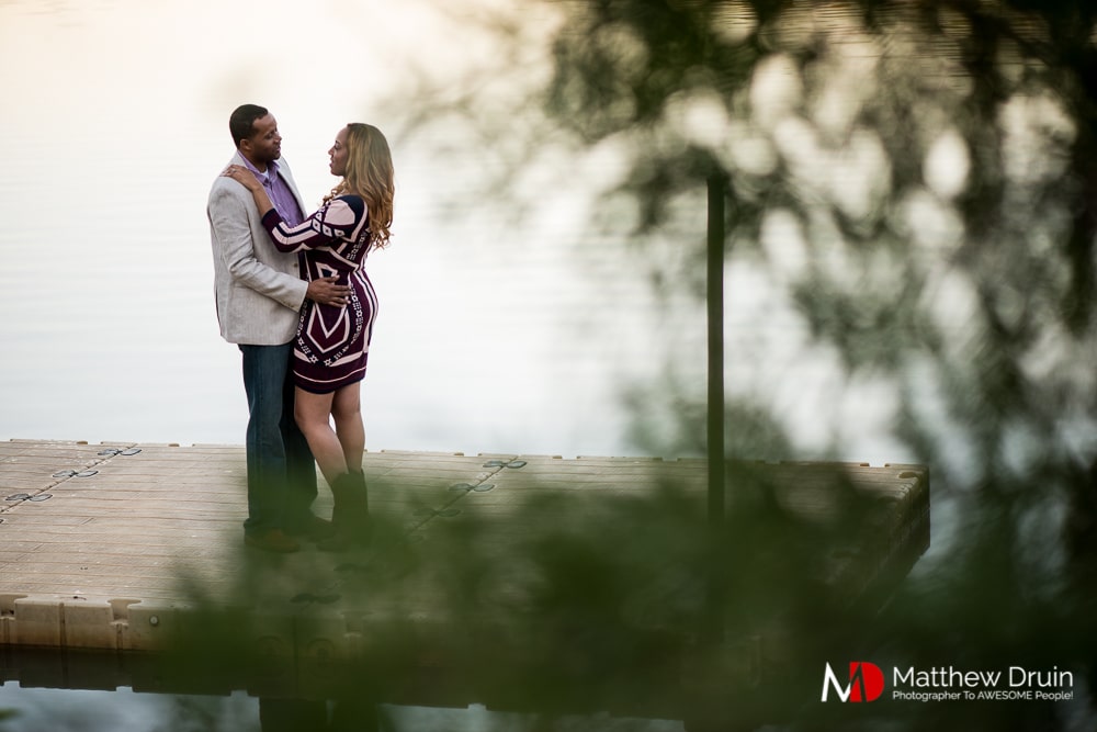 Engaged couple standing by lake at sunset at Basketball Themed Atlanta Engagement Session