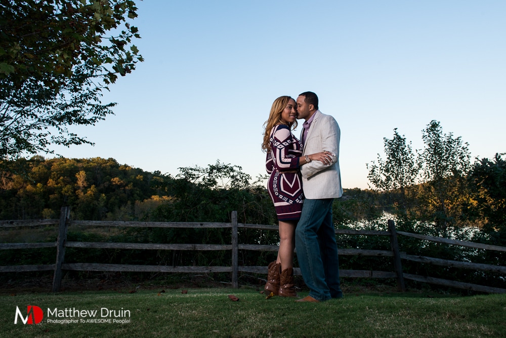 Engaged couple kissing by lake at sunset at Basketball Themed Atlanta Engagement Session