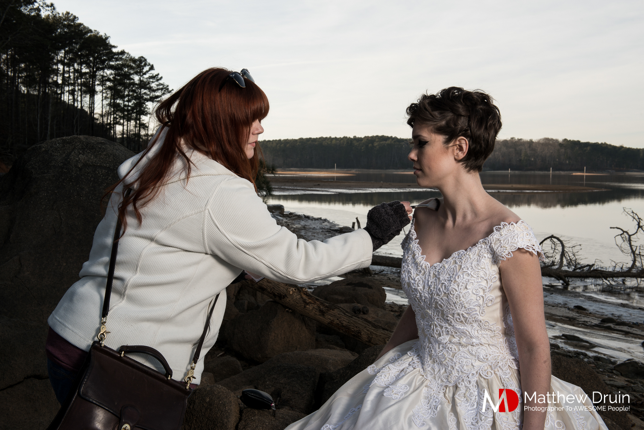 Makeup artist applying makeup on bride in empty lake in Acworth Georgia