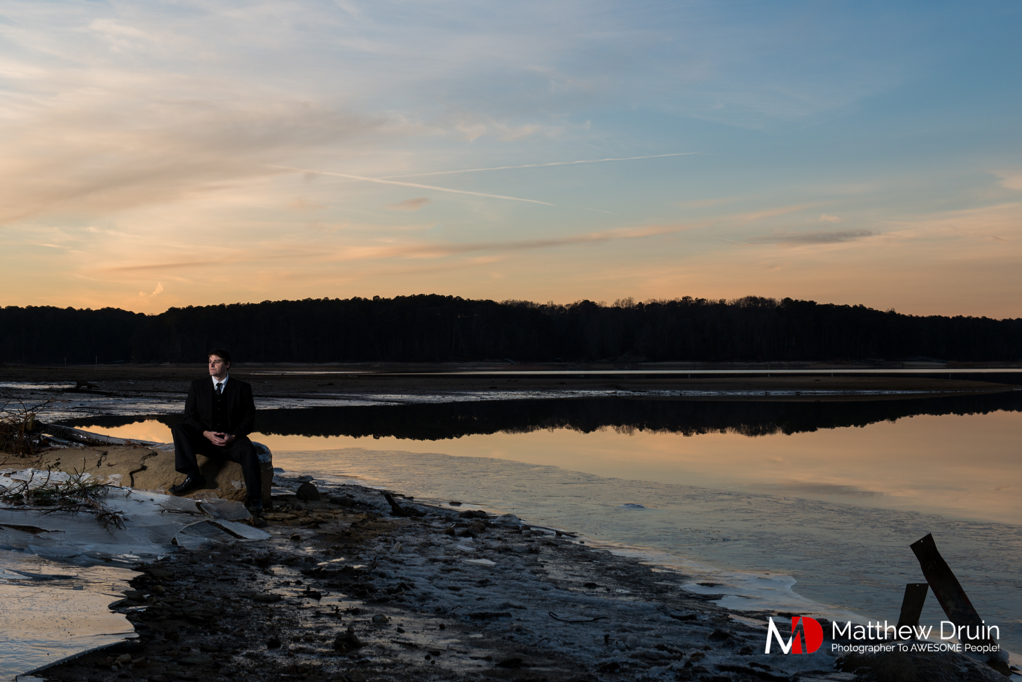 Groom sitting in frozen lake in Atlanta at sunset